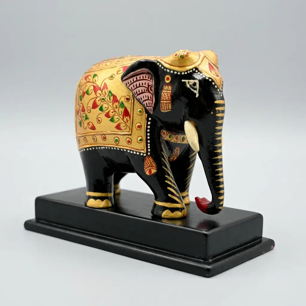 Front angled view of a black and gold wooden elephant memento with ivory-coloured tusks and a downward trunk