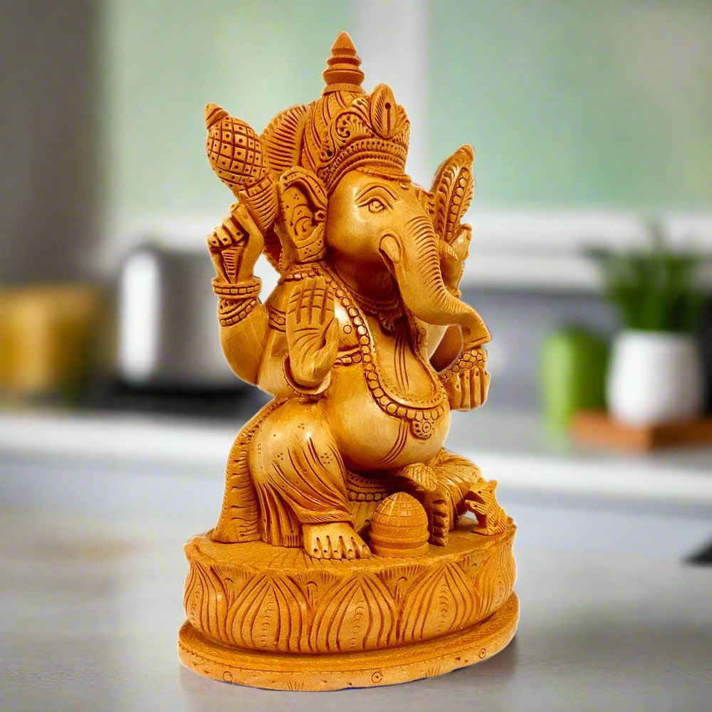 Wooden Ganesha statue sitting on lotus flower, hand-carved from Kadamba wood for puja decor.