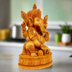Wooden Ganesha statue sitting on lotus flower, hand-carved from Kadamba wood for puja decor.