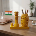 Rear view of a wooden pen holder with carved animal motifs and three pens, beside an Ashok Pillar and Indian flag on a wooden base
