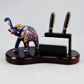 Wooden pen stand with a blue Meenakari elephant, two black pens and a visiting card holder