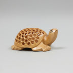 Wooden tortoise statue showing the intricate lattice undercut carving design on its back.