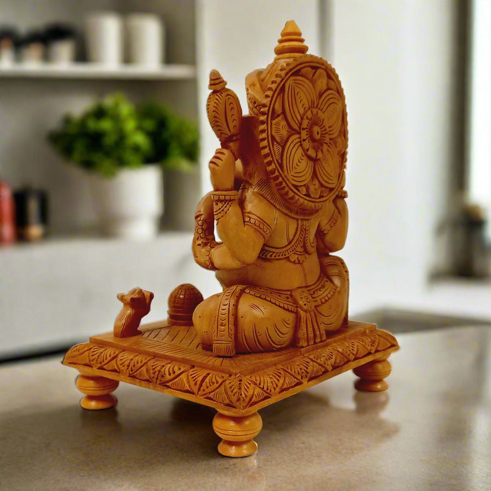 Auspicious wooden Ganesh idol seated on wooden chowki, adorned with fine artistic work, ideal for home worship.

