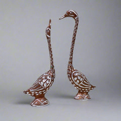 Decorative pair of metal swans polished in copper and silver, symbolizing love and beauty for home decor.

