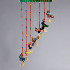 Slant design peacock toran made from paper mache, featuring beads, thread, and decorative stick.
