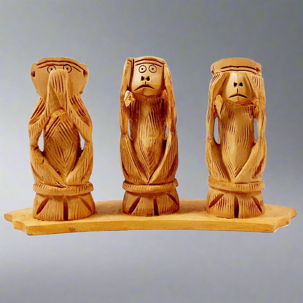 Gandhi-inspired wooden monkey carving with eyes closed, see no evil pose.