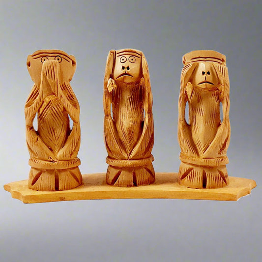 Gandhi-inspired wooden monkey carving with eyes closed, see no evil pose.