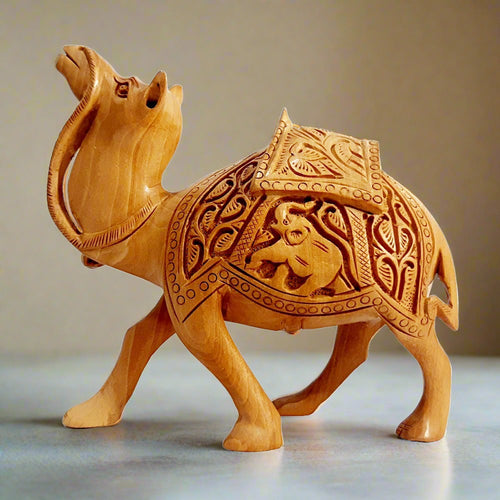 A magnificent hand-carved wooden camel idol featuring intricate deep carvings on the saddle and a unique regal posture.