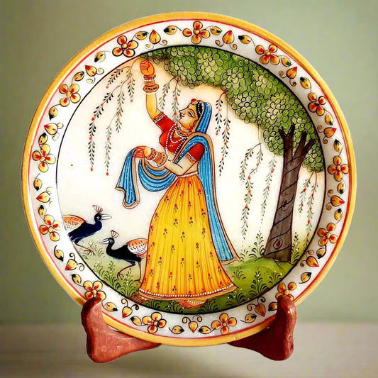 A handmade marble plate with a painting of a lady plucking flowers and two peacocks.