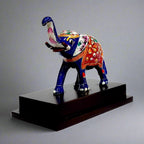 Side view of multicolour emboss meenakari elephant on wooden platform.