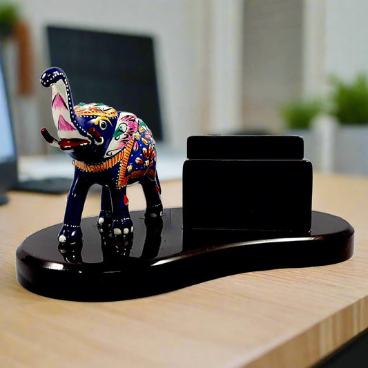 A metal elephant with Meenakari painting on a wooden desk organizer, a great piece for office decor.