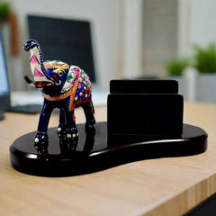 A metal elephant with Meenakari painting on a wooden desk organizer, a great piece for office decor.