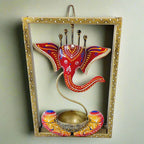 A Ganesha idol inside a metal frame, featuring a tealight holder at the base.