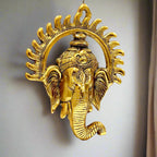 A golden metal Ganesha wall hanging with the unique shape of the sun on his face.