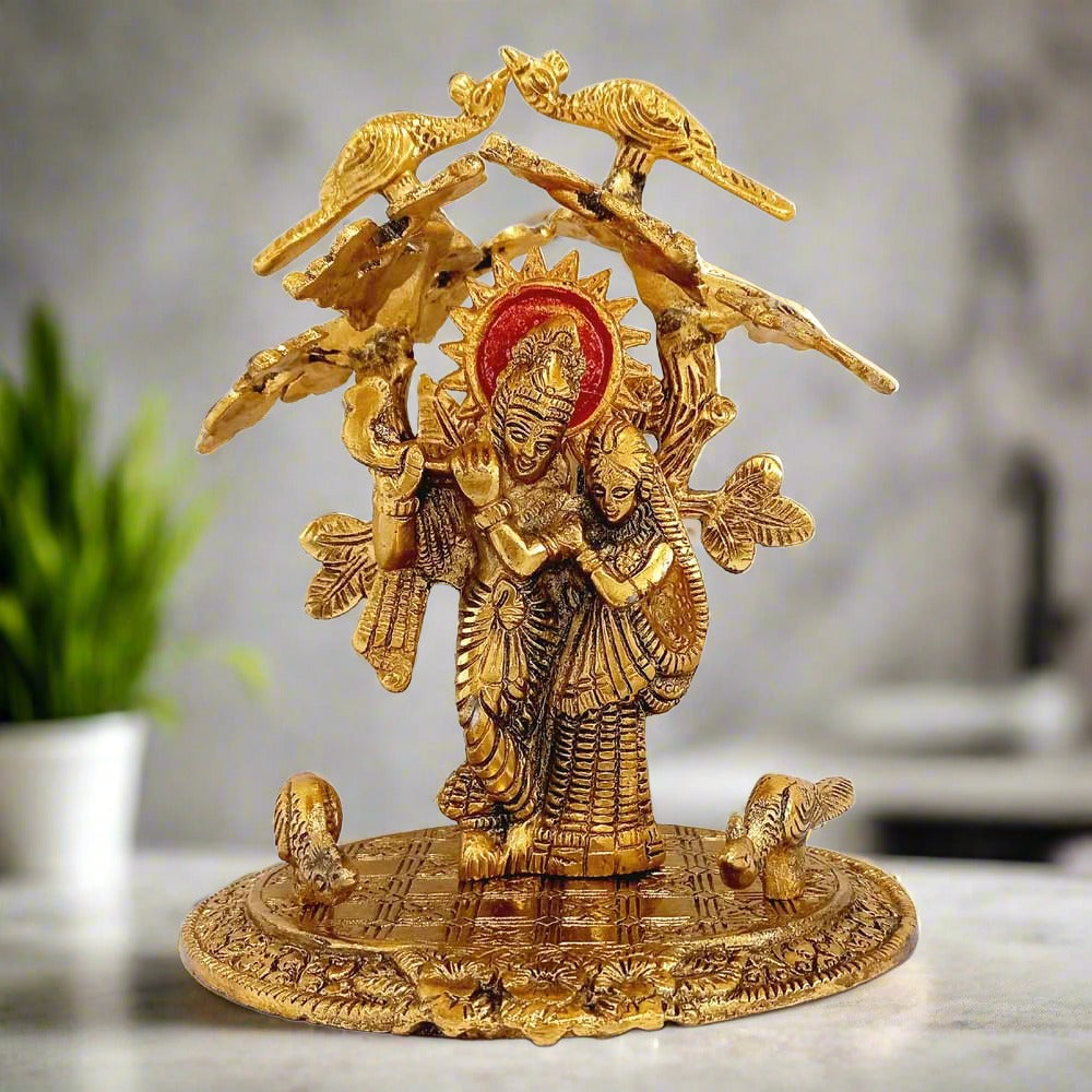 Metal Radha Krishna idol in gold oxidized finish, depicting Radha and Krishna standing together under a tree