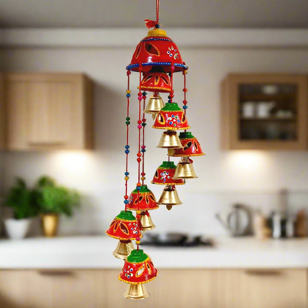 A decorative bell toran made of papier-mâché, adorned with golden bells, beads, and threads.