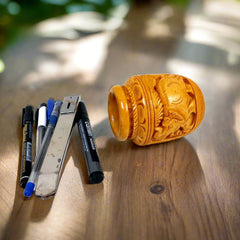 A pot design wooden pen stand with elephant carvings, perfect for keeping on an office table.