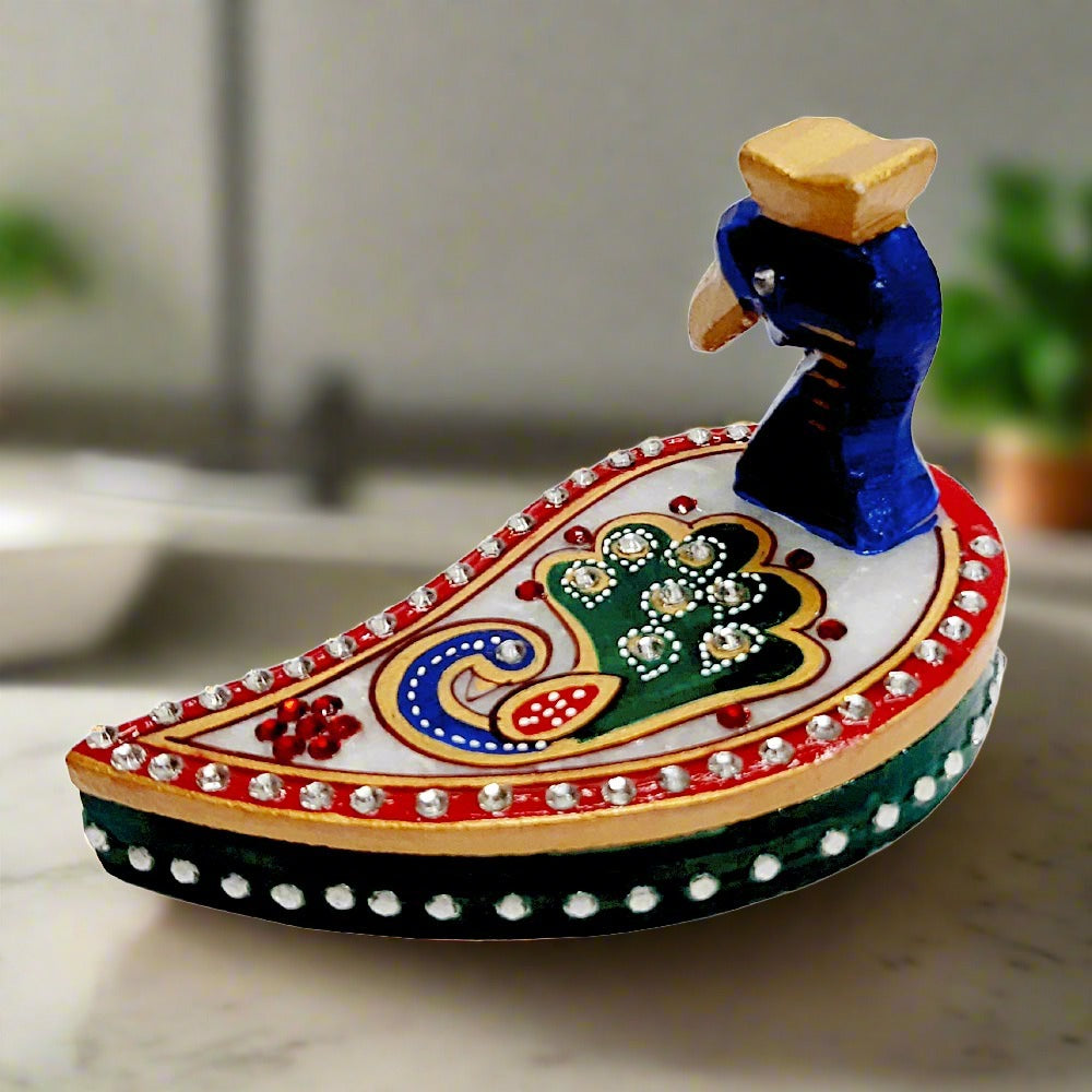 A beautiful hand-painted kumkum box made of pure marble with a peacock design.