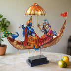 A Radha Krishna statue sitting in a boat, with a peacock, umbrella, and decorative flag.