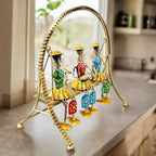 A beautiful example of Rajasthani art with three dolls swinging on a jhula, with moving legs.