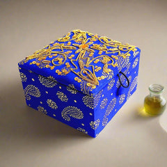 Small silk fabric box adorned with fine zardosi hand embroidery using golden wire and sequins, suitable for storing small jewelry.