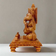 Spiritual wooden Ganesh idol sitting on wooden chowki with hand-carved details, perfect for prayer rooms.
