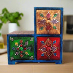 Front view of colorful hand-painted triangular wooden paint box for home decor with three drawers