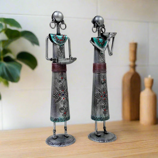 Set of two tribal art metal candle holders featuring standing tribal ladies with bowls for candles, decorated with silver oxidized color and emboss painting.